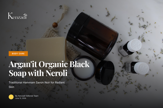 Open jar of dark brown Moroccan black soap with a wooden spoon and neroli blossoms
