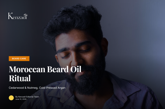 A man with a well-groomed beard applying oil from a glass dropper bottle, with argan nuts and cedarwood